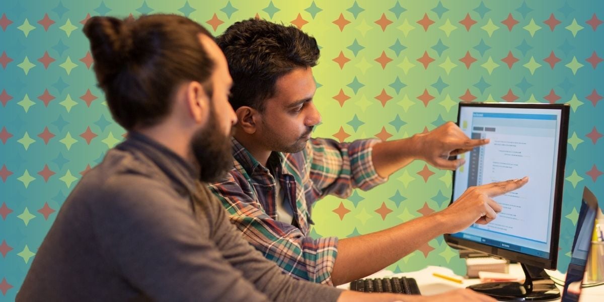 Two young men actively engaged in the computer screen in front of them, pointing at details and discussing details and settings for printing and proofing. The actual content of the screen is illegible to the viewer.